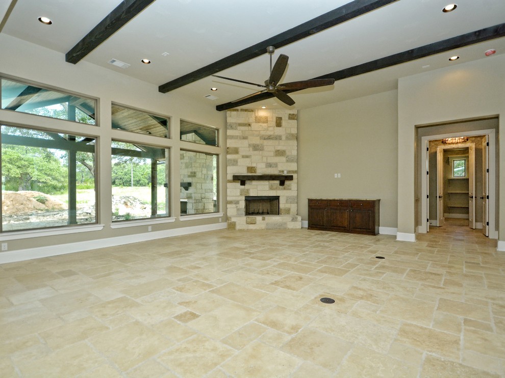 This is an example of a medium sized rustic formal enclosed living room in Austin with beige walls, travertine flooring, a standard fireplace, a stone fireplace surround and no tv.