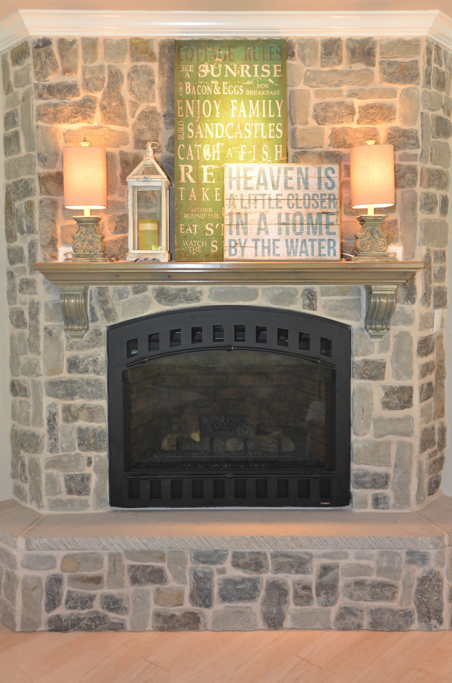 ポートランドにあるラグジュアリーな広いカントリー風のおしゃれなLDK (グレーの壁、淡色無垢フローリング、コーナー設置型暖炉、石材の暖炉まわり、ベージュの床) の写真