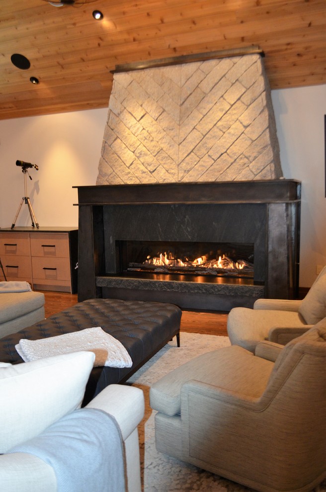 シアトルにあるラグジュアリーな広いインダストリアルスタイルのおしゃれなリビング (ベージュの壁、無垢フローリング、標準型暖炉、金属の暖炉まわり、壁掛け型テレビ、茶色い床) の写真