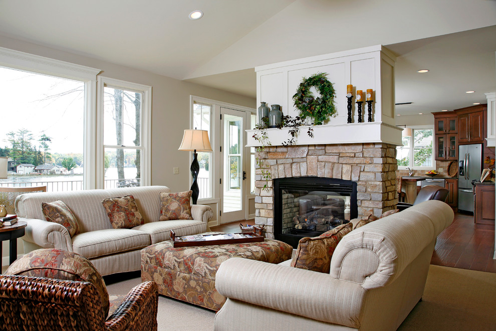 Inspiration for a large timeless formal and open concept dark wood floor and brown floor living room remodel in Grand Rapids with a stone fireplace, beige walls, a two-sided fireplace and no tv