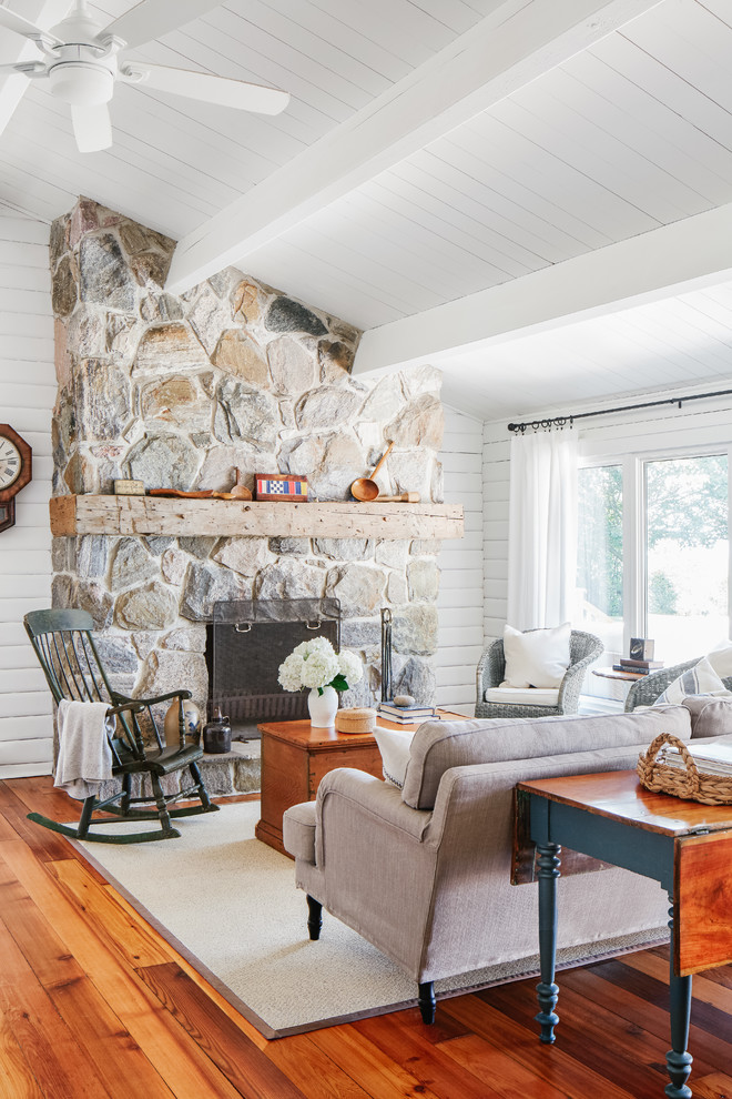 Inspiration for a mid-sized coastal open concept medium tone wood floor and brown floor living room remodel in Toronto with white walls, a standard fireplace, a stone fireplace and no tv