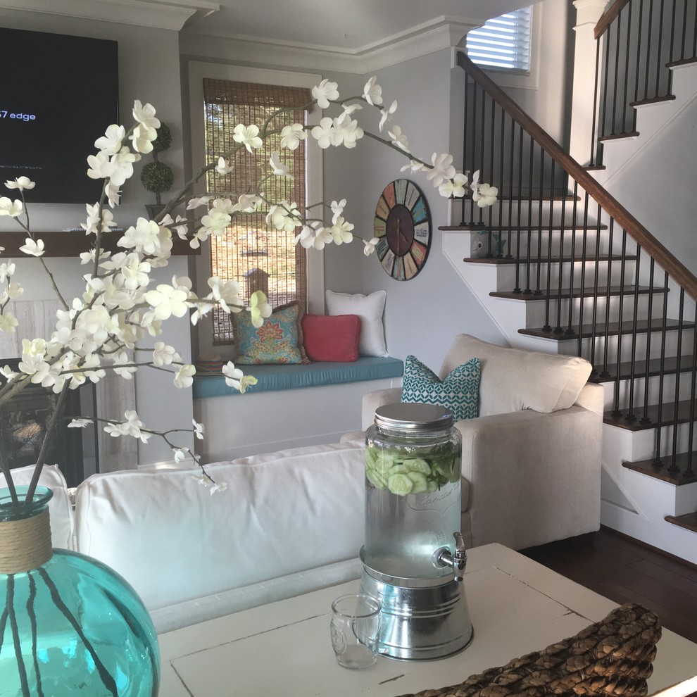 На фото: открытая гостиная комната среднего размера в морском стиле с паркетным полом среднего тона, серыми стенами, стандартным камином, телевизором на стене и коричневым полом