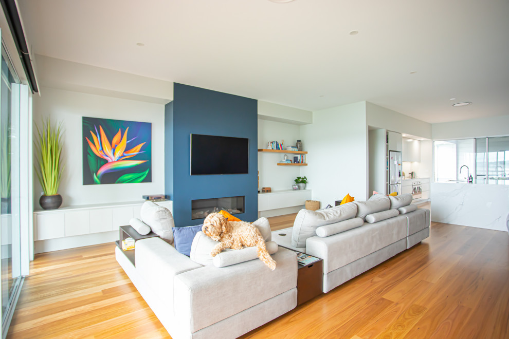 Offenes Modernes Wohnzimmer mit weißer Wandfarbe, braunem Holzboden, Gaskamin, TV-Wand und braunem Boden in Newcastle - Maitland