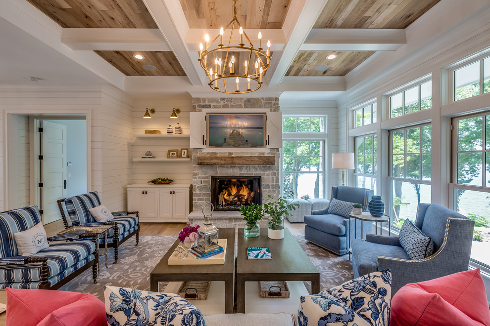 Photo of a nautical formal living room in Minneapolis with white walls, light hardwood flooring, a standard fireplace, a stone fireplace surround, a concealed tv and feature lighting.