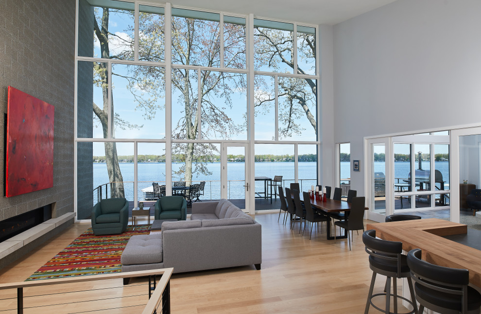 Стильный дизайн: открытая гостиная комната в стиле модернизм с серыми стенами, светлым паркетным полом, горизонтальным камином, фасадом камина из кирпича, скрытым телевизором и коричневым полом - последний тренд