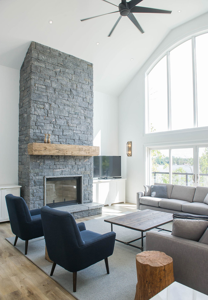 Large transitional open concept medium tone wood floor and brown floor living room photo in Toronto with white walls, a standard fireplace, a stone fireplace and a tv stand