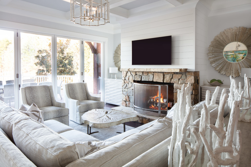 Inspiration for a large coastal formal enclosed living room in Charlotte with white walls, dark hardwood flooring, a standard fireplace, a stone fireplace surround, a wall mounted tv and brown floors.
