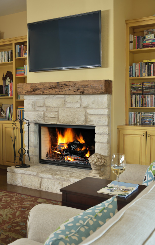 オースティンにある広いトラディショナルスタイルのおしゃれなLDK (黄色い壁、コンクリートの床、標準型暖炉、石材の暖炉まわり、壁掛け型テレビ) の写真