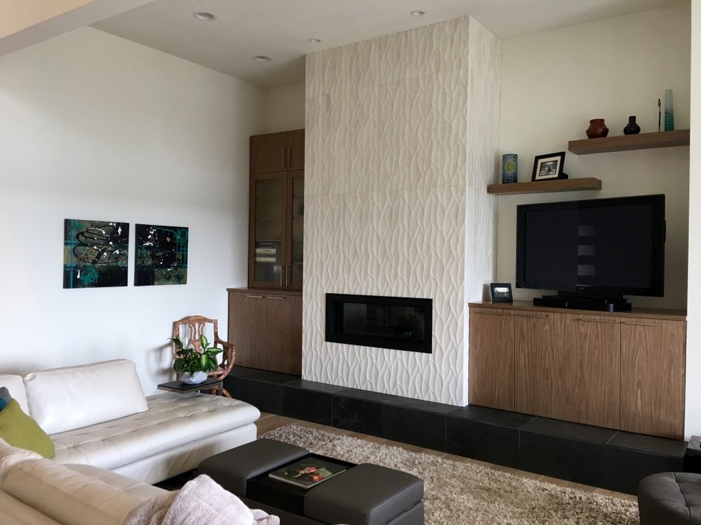 Modern inredning av ett stort allrum med öppen planlösning, med vita väggar, ljust trägolv, en hängande öppen spis, en spiselkrans i trä, en fristående TV och vitt golv