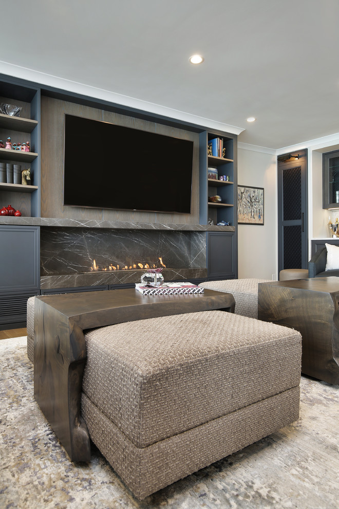 Large traditional open plan living room in Chicago with a home bar, grey walls, light hardwood flooring, a ribbon fireplace, a stone fireplace surround and a built-in media unit.
