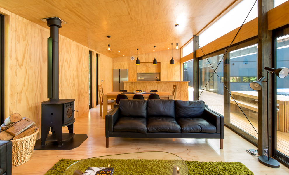 Idee per un soggiorno country aperto con pavimento in compensato e stufa a legna