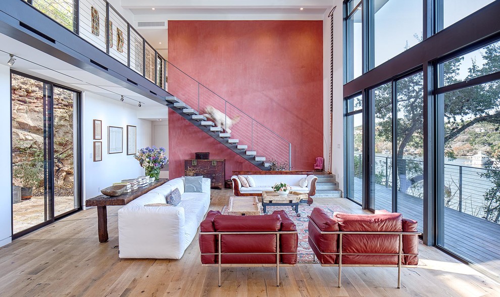 Aménagement d'un grand salon moderne ouvert avec un mur rouge et parquet clair.