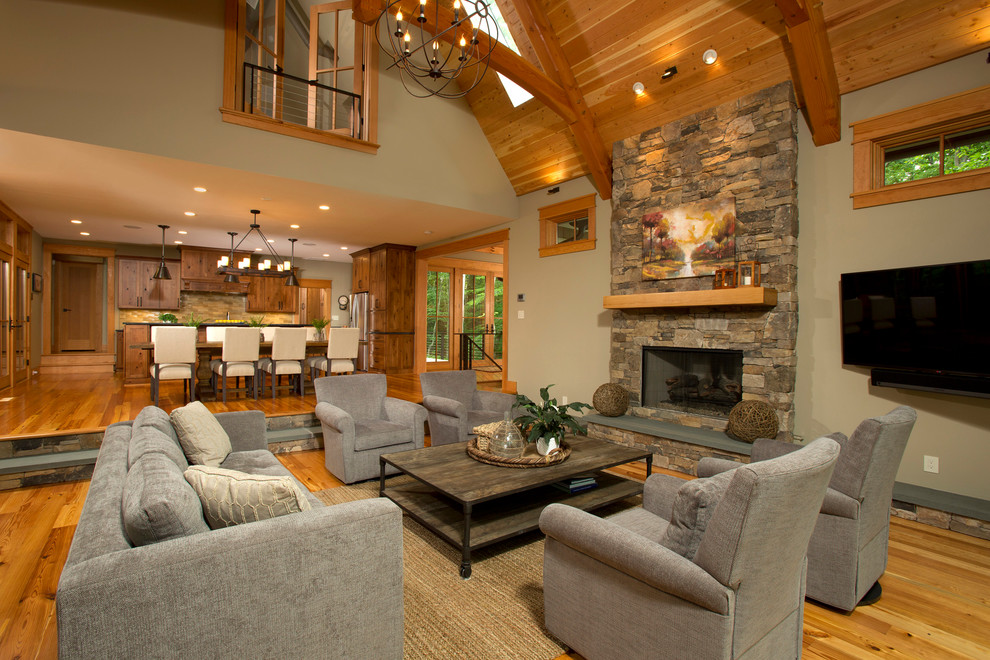 Large rustic formal open plan living room in DC Metro with beige walls, medium hardwood flooring, a stone fireplace surround, a wall mounted tv, a standard fireplace and brown floors.