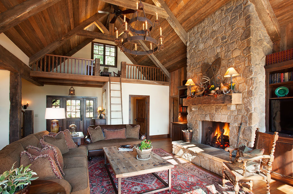 Example of a mountain style open concept light wood floor living room library design in Other with a standard fireplace, a stone fireplace and a media wall