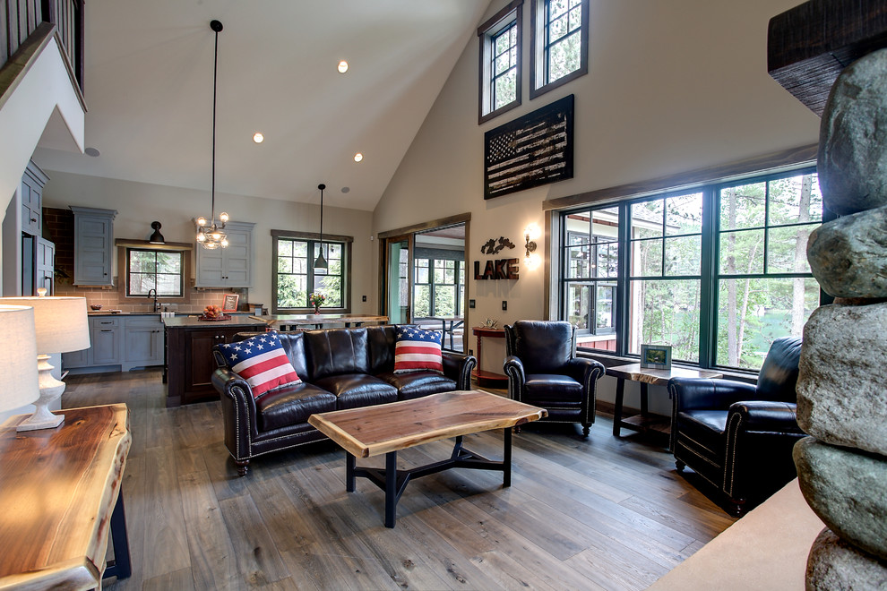 Réalisation d'un salon craftsman de taille moyenne et ouvert avec un mur beige, un sol en bois brun, une cheminée standard, un manteau de cheminée en pierre et un téléviseur fixé au mur.