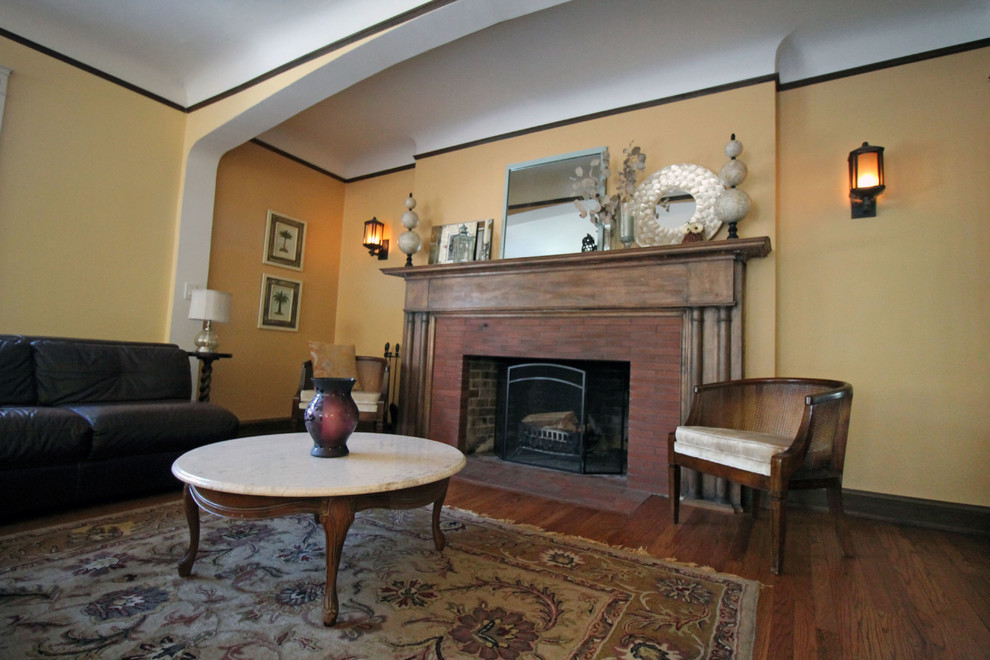 Großes, Repräsentatives, Offenes Klassisches Wohnzimmer mit gelber Wandfarbe, braunem Holzboden, Kamin und Kaminumrandung aus Backstein in Chicago