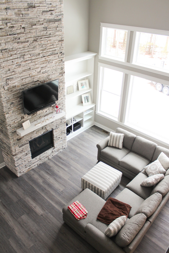 Inspiration for a contemporary vinyl floor and brown floor living room remodel in Grand Rapids with a standard fireplace, a stone fireplace and a wall-mounted tv