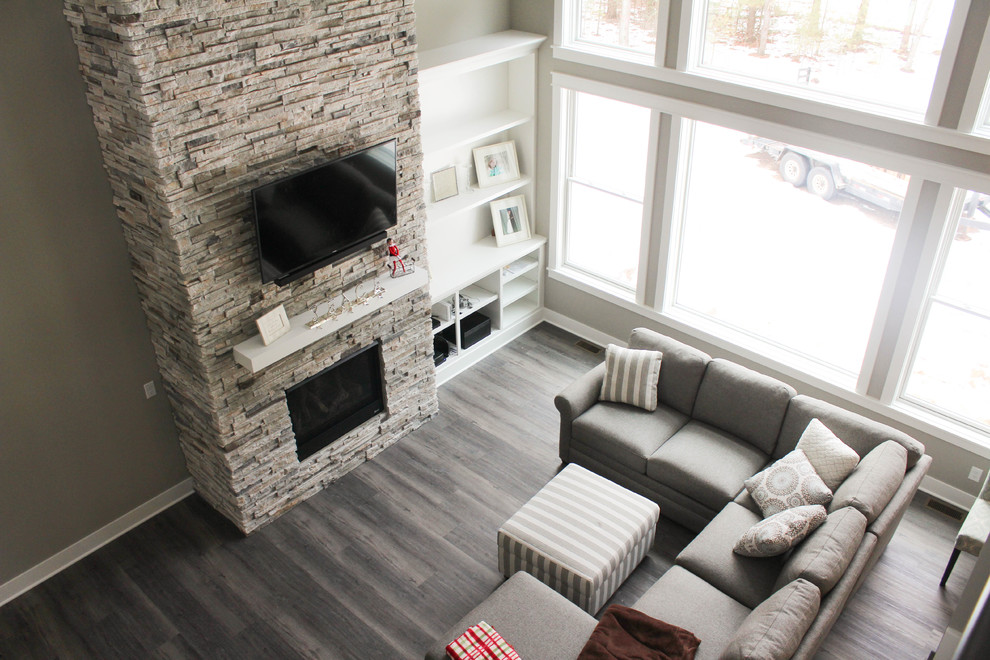 Modernes Wohnzimmer mit Vinylboden, Kamin, Kaminumrandung aus Stein, TV-Wand und braunem Boden in Grand Rapids