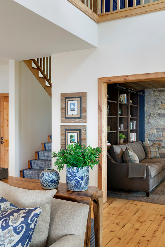 Large beach style mezzanine living room in Minneapolis with light hardwood flooring, a standard fireplace, a stacked stone fireplace surround and a vaulted ceiling.