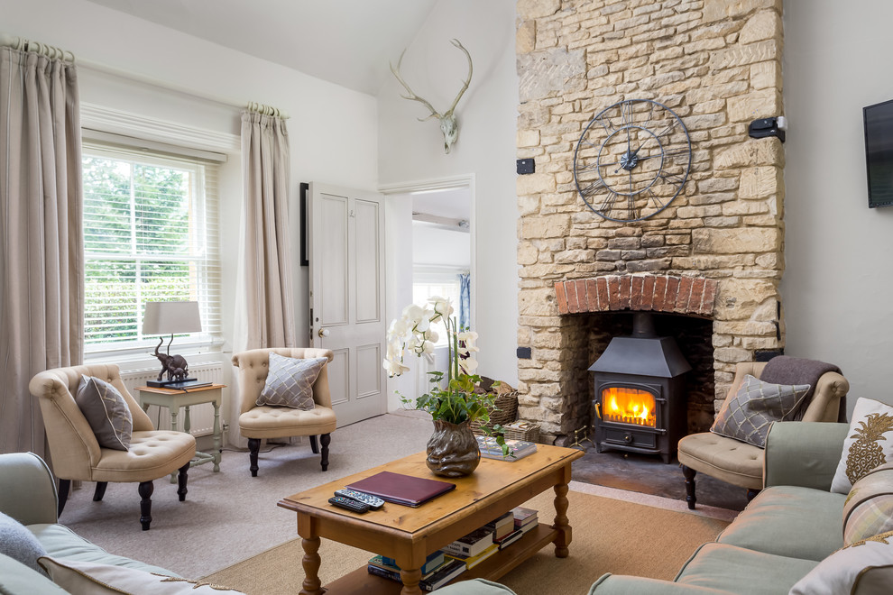 Example of a large farmhouse formal and enclosed carpeted living room design in Gloucestershire with white walls, a wood stove, a stone fireplace and a wall-mounted tv