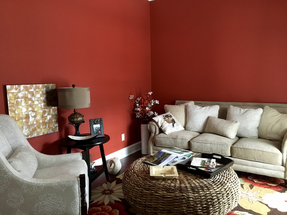 Esempio di un piccolo soggiorno american style chiuso con libreria, pareti rosse, parquet scuro, nessun camino, nessuna TV e pavimento marrone