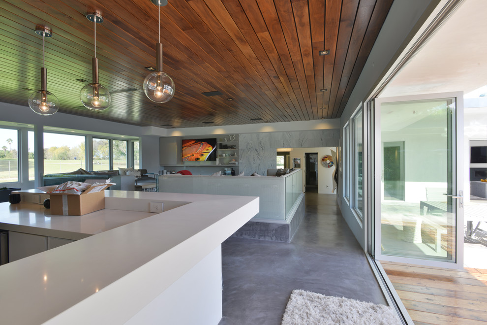 Идея дизайна: большая открытая гостиная комната в стиле модернизм с серыми стенами, бетонным полом и телевизором на стене без камина