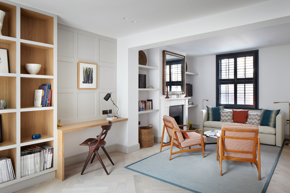 Kleine, Fernseherlose, Offene Moderne Bibliothek mit beiger Wandfarbe, hellem Holzboden, Kamin und Kaminumrandung aus Stein in London