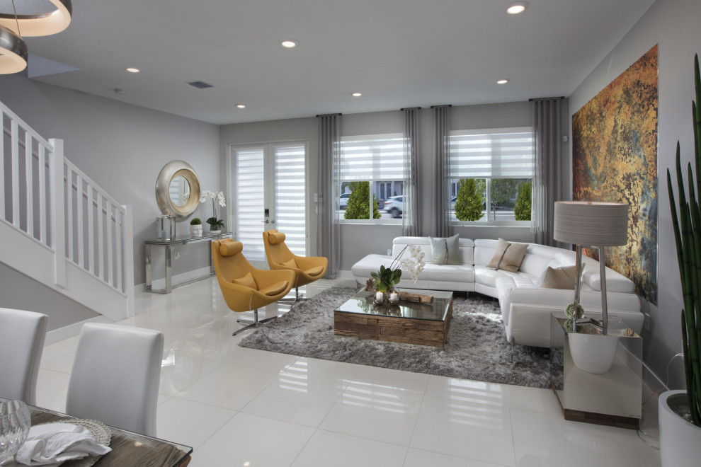 Cette image montre un grand salon design ouvert avec un mur gris, un sol en carrelage de porcelaine et un sol blanc.