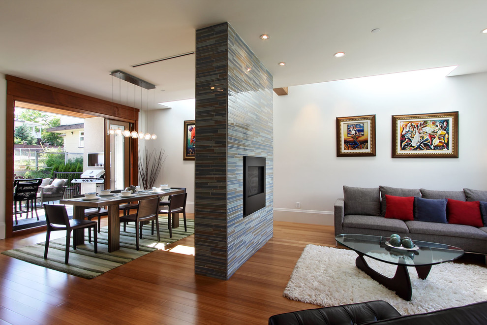 Example of a trendy formal and open concept medium tone wood floor living room design in Vancouver with white walls, a two-sided fireplace and a tile fireplace