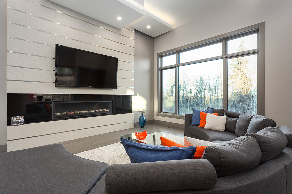 Design ideas for a large modern open plan living room in Edmonton with grey walls, medium hardwood flooring, a ribbon fireplace, a tiled fireplace surround, a wall mounted tv and brown floors.