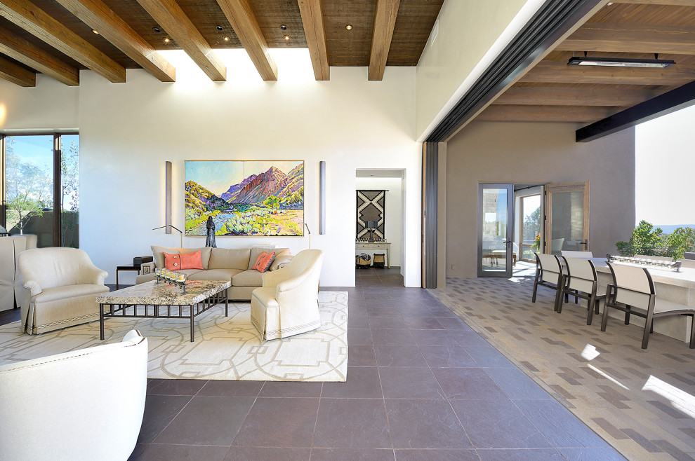 Example of a mid-sized southwest enclosed porcelain tile and gray floor living room design in Albuquerque with white walls, a standard fireplace, a stone fireplace and a wall-mounted tv