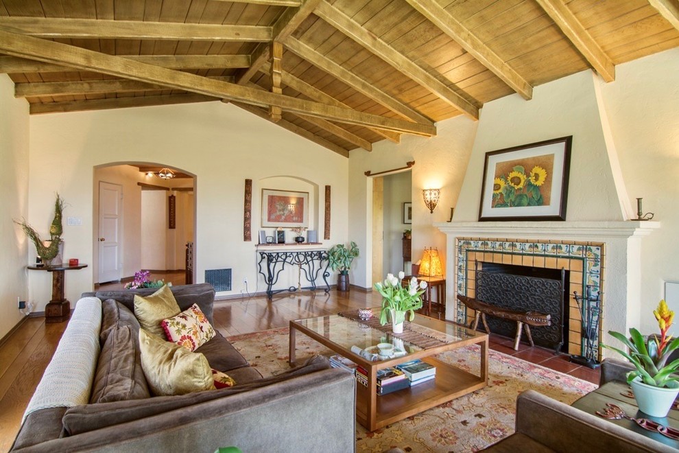 Photo of a mediterranean formal enclosed living room in Los Angeles with beige walls, medium hardwood flooring, a standard fireplace and a tiled fireplace surround.