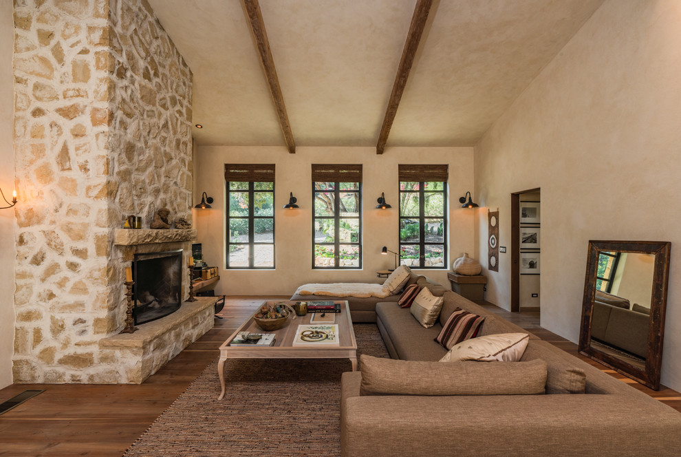 Idee per un soggiorno american style con pareti beige, parquet scuro, camino classico, cornice del camino in pietra e pavimento marrone