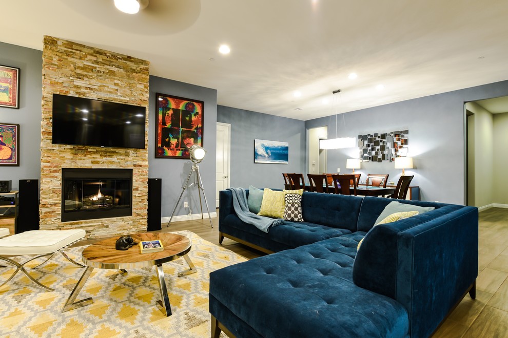 Foto de salón abierto minimalista grande con paredes azules, suelo de baldosas de cerámica, todas las chimeneas, marco de chimenea de piedra y televisor colgado en la pared
