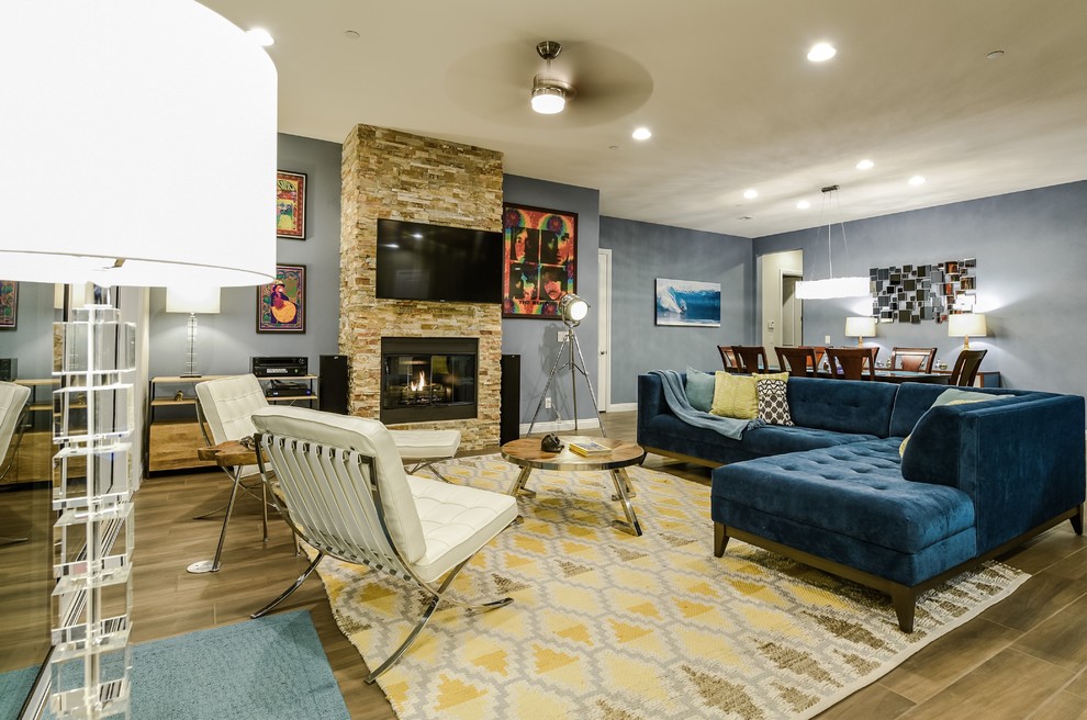 アトランタにある高級な広いモダンスタイルのおしゃれなLDK (青い壁、セラミックタイルの床、標準型暖炉、石材の暖炉まわり、壁掛け型テレビ) の写真
