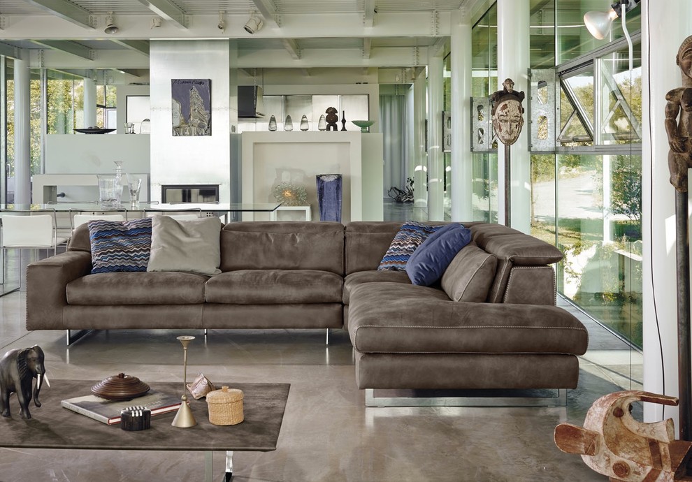 На фото: парадная, открытая гостиная комната в современном стиле с бетонным полом и коричневым диваном без телевизора