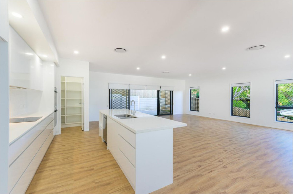 Imagen de salón abierto actual de tamaño medio con paredes blancas, suelo vinílico, televisor independiente y suelo beige