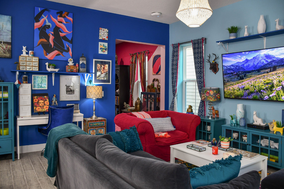 Imagen de salón para visitas abierto bohemio grande con paredes azules y televisor colgado en la pared