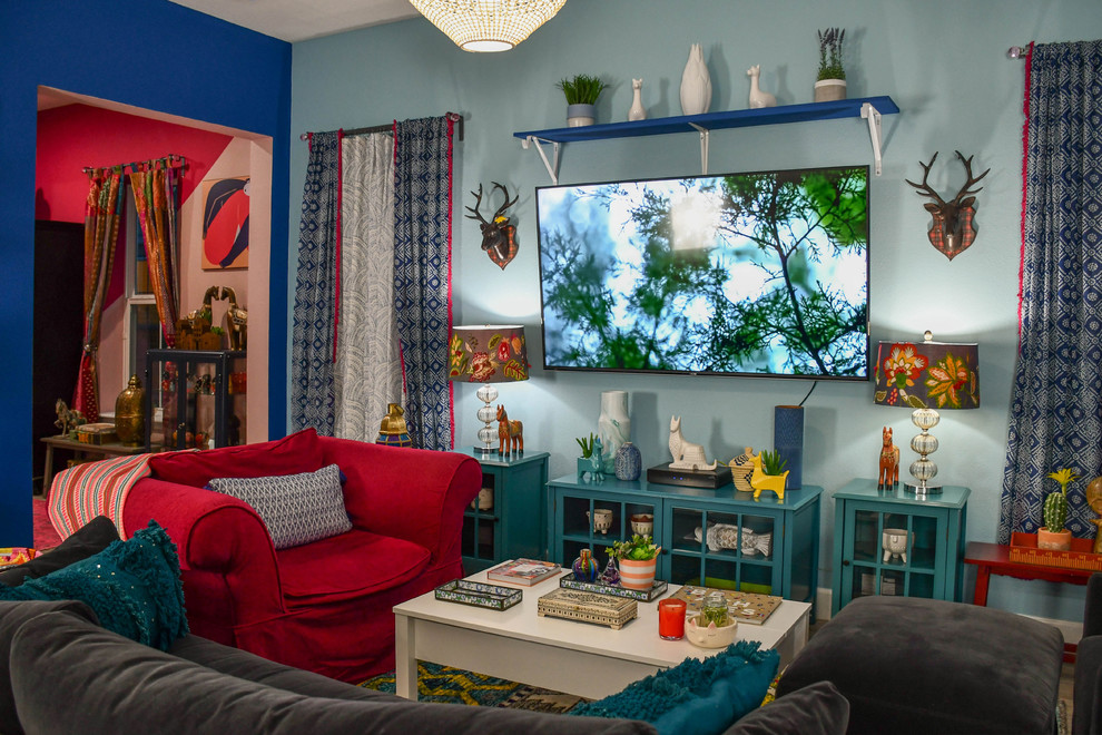 На фото: большая изолированная гостиная комната в стиле фьюжн с синими стенами и телевизором на стене с