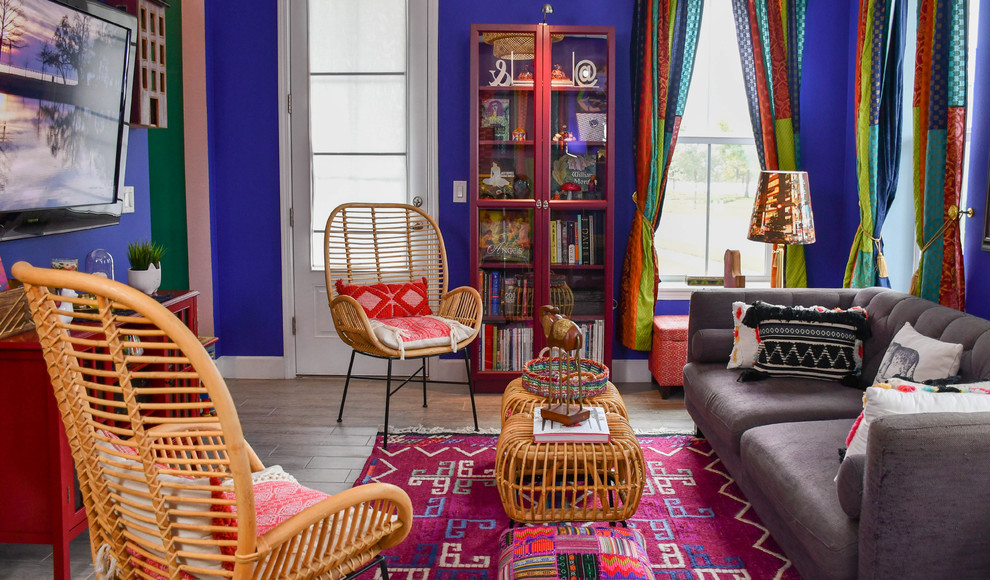 Foto de salón para visitas abierto ecléctico grande con paredes púrpuras, suelo de baldosas de porcelana, televisor colgado en la pared y suelo gris