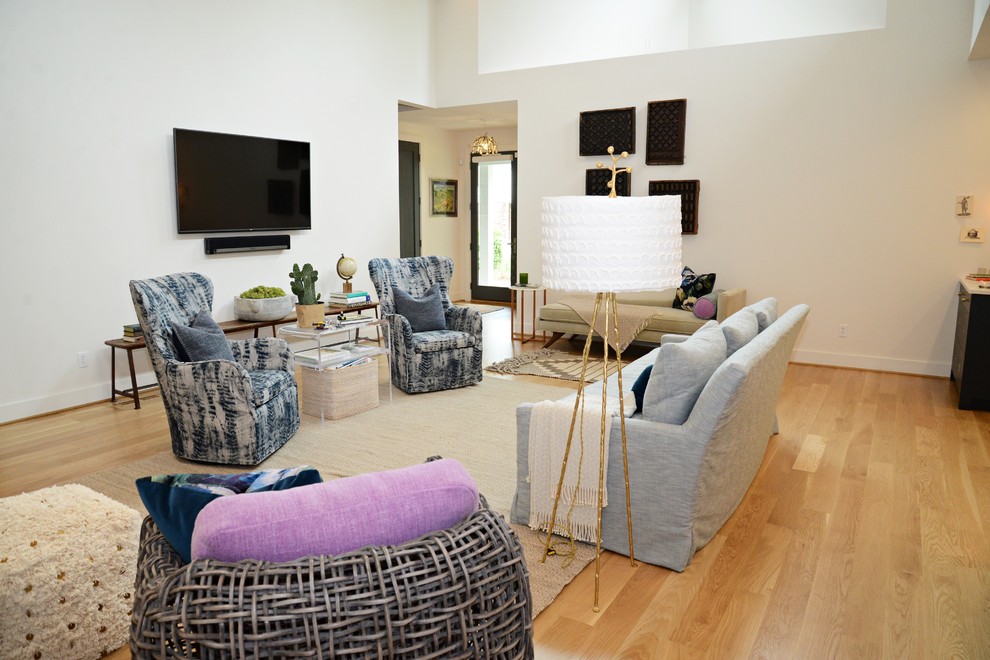 Стильный дизайн: открытая гостиная комната в стиле кантри с белыми стенами, светлым паркетным полом, двусторонним камином и фасадом камина из дерева - последний тренд