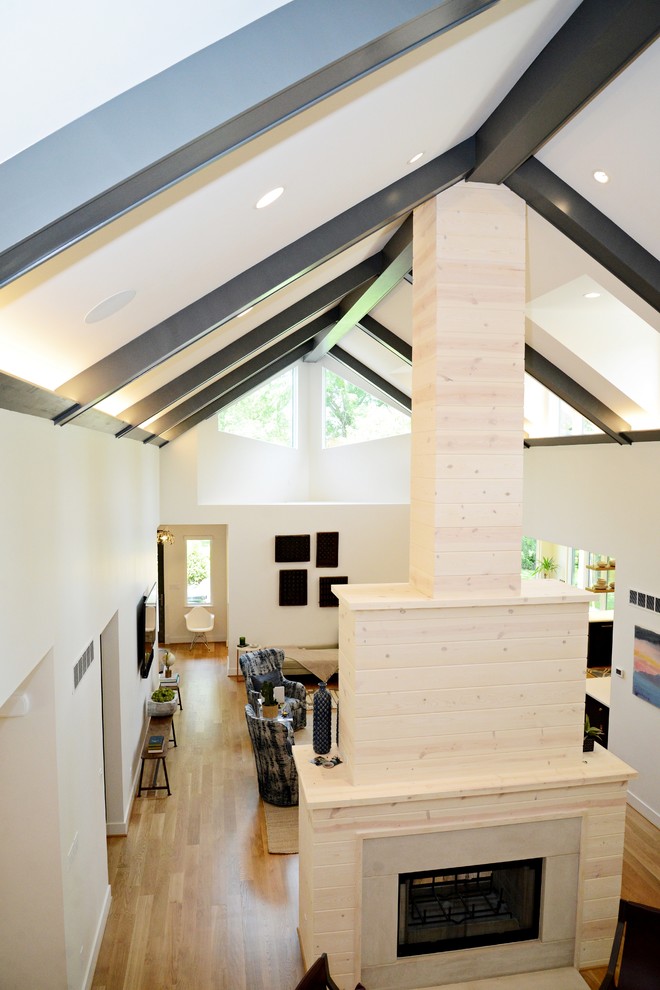 Offenes Landhaus Wohnzimmer mit weißer Wandfarbe, hellem Holzboden, Tunnelkamin und Kaminumrandung aus Holz in St. Louis