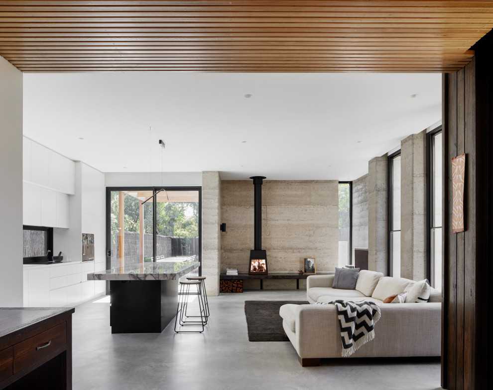 Mittelgroßes, Offenes Modernes Wohnzimmer mit weißer Wandfarbe, Betonboden, Kaminofen und grauem Boden in Melbourne