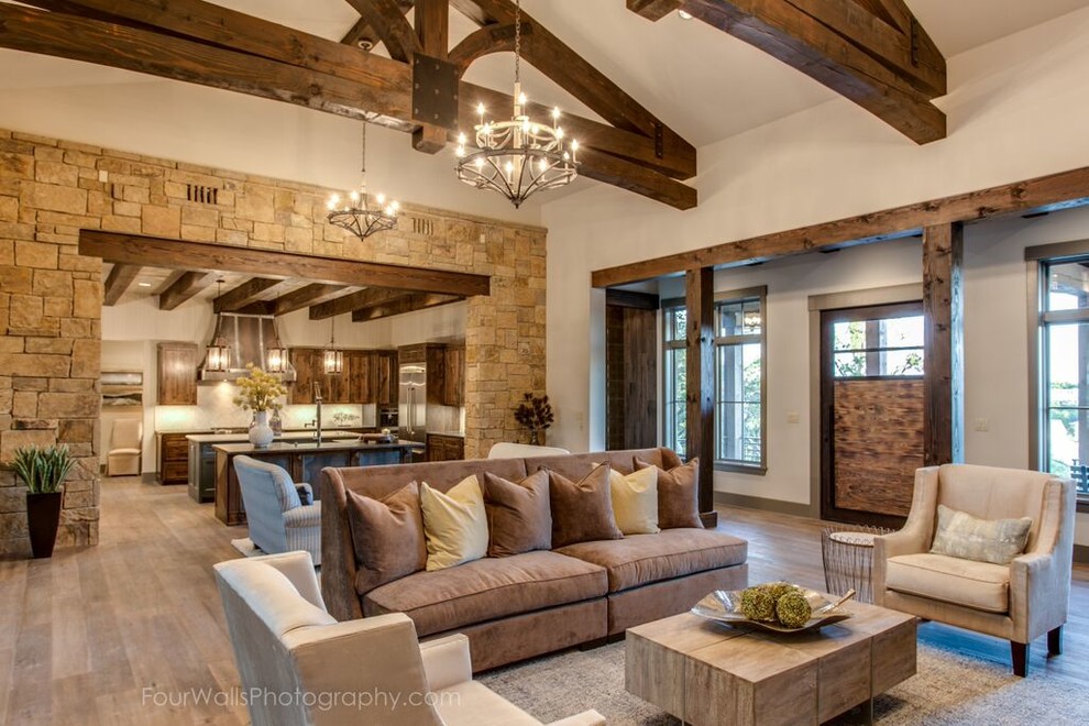 Design ideas for a large rustic formal open plan living room in Austin with beige walls, medium hardwood flooring, a standard fireplace and a wall mounted tv.