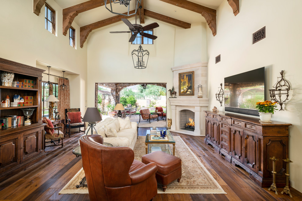 Klassisches Wohnzimmer mit beiger Wandfarbe, braunem Holzboden, Kamin, TV-Wand und braunem Boden in Phoenix