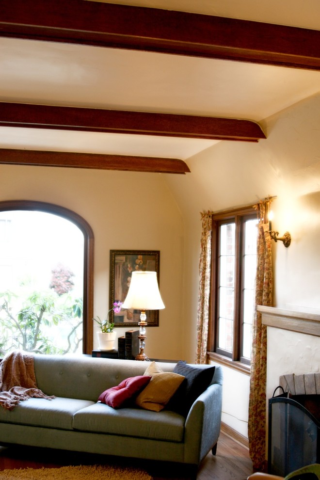 Klassisches Wohnzimmer mit beiger Wandfarbe, braunem Holzboden, Kamin und verputzter Kaminumrandung in Seattle