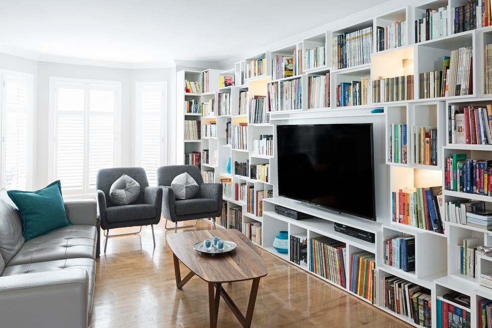 Imagen de biblioteca en casa abierta actual de tamaño medio sin chimenea con paredes beige, suelo de madera clara, televisor colgado en la pared y suelo marrón