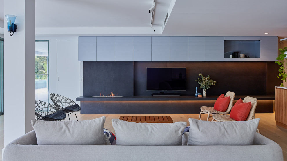 Immagine di un grande soggiorno design aperto con parquet chiaro, TV a parete, pavimento marrone, pareti bianche e camino lineare Ribbon