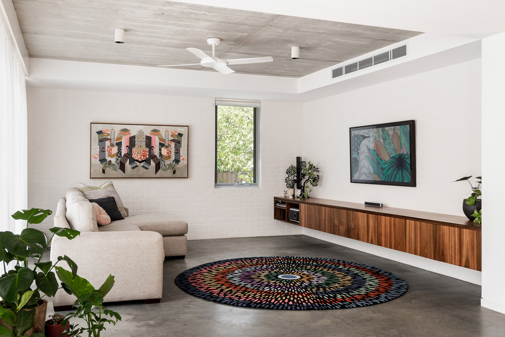 Cette image montre un salon design avec un mur blanc, sol en béton ciré, aucune cheminée et un sol gris.