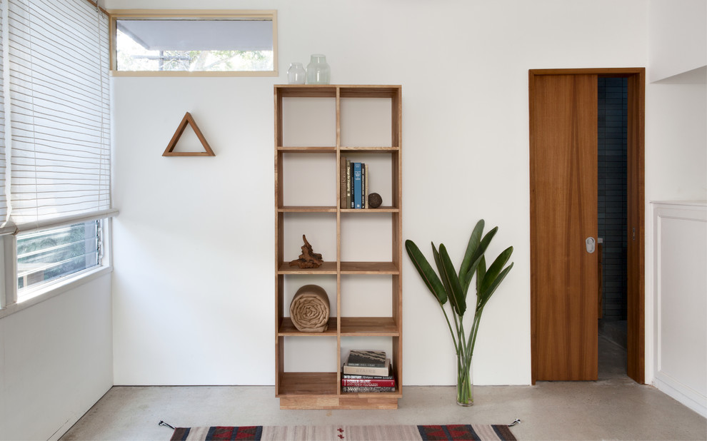 Idee per un piccolo soggiorno contemporaneo chiuso con libreria, pareti bianche e pavimento in cemento